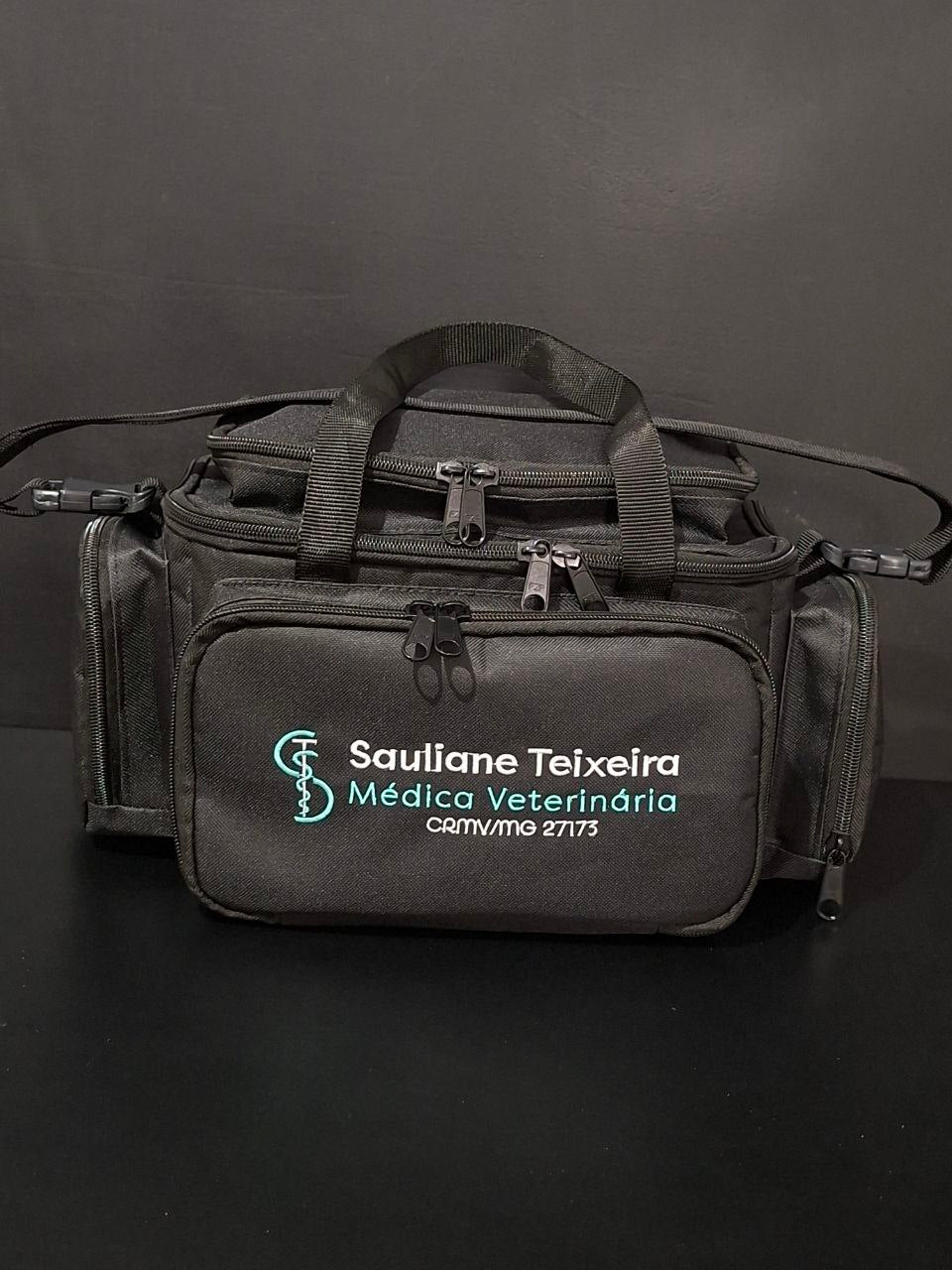 Bolsa profissional personalizada com a logo do cliente, cor preta com alça e tira colo. Visão frontal