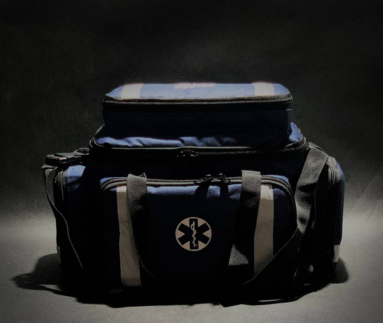 bolsa de APH. Imagem frontal, bolsa na cor azul, bordado da Cruz da Vida e faixas refletivas